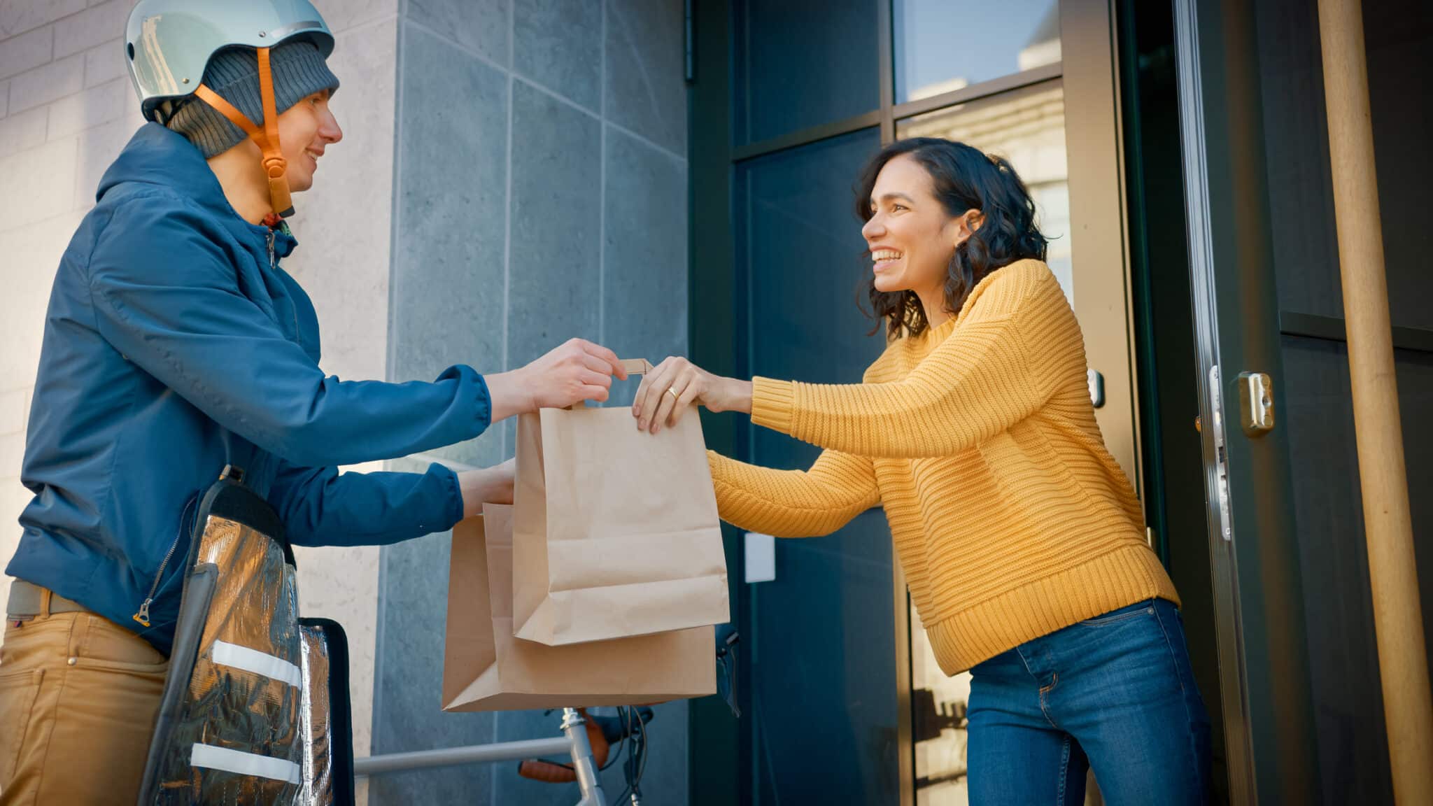 Jeune femme au pied de son immeuble recevant une livraison de produit venant d'un e-commerce alimentaire