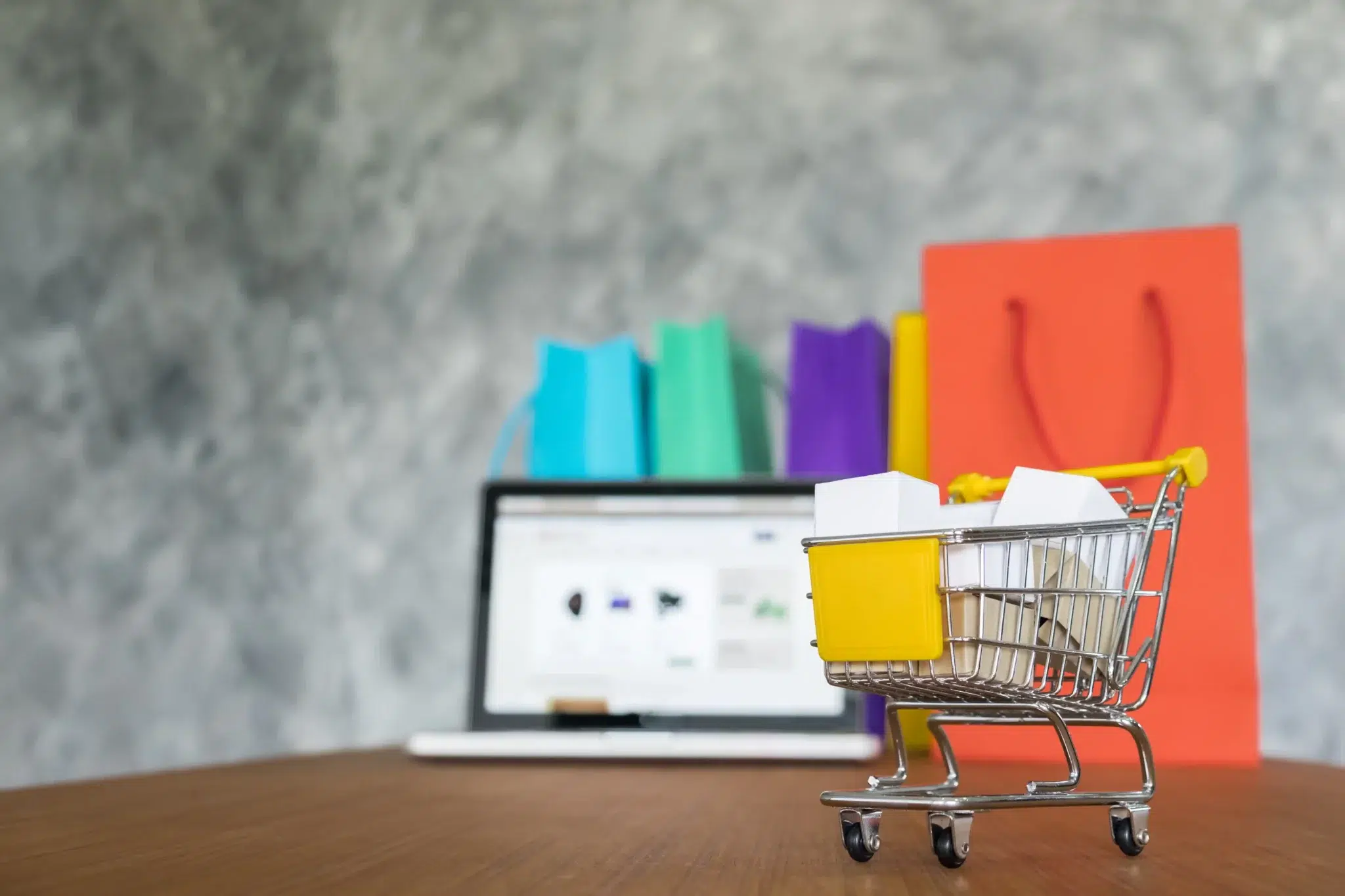 Panier avec achat et colis devant site e-commerce