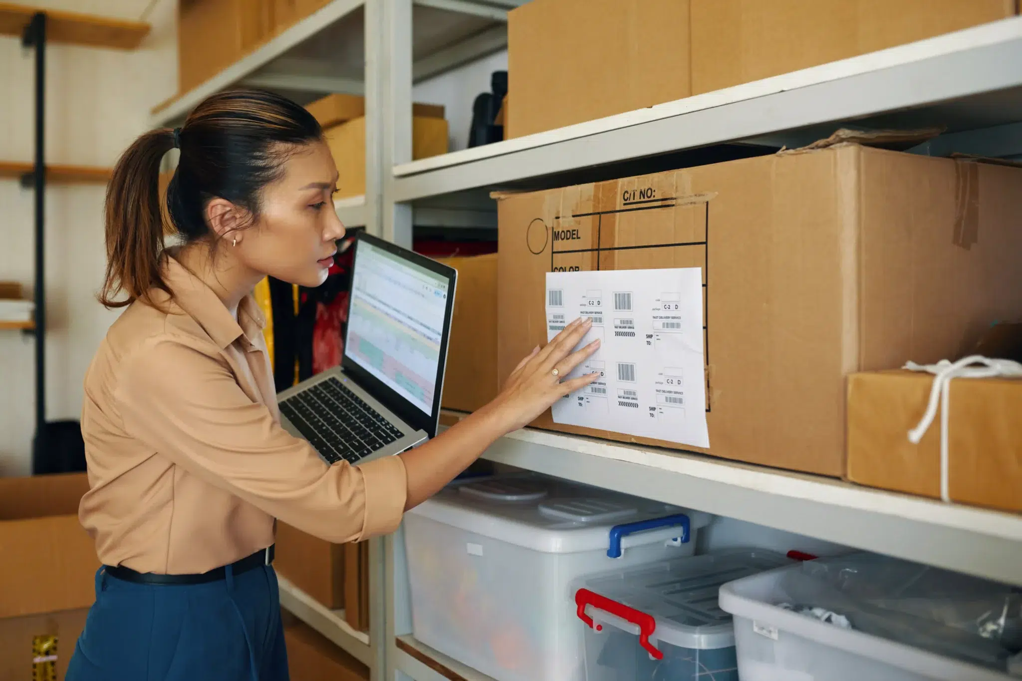 Femme vérifiant l'étiquette d'un colis dans un entrepôt pour stockage produits sensibles e-commerce